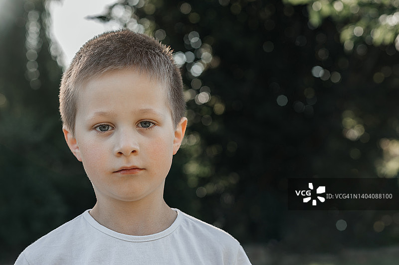 一个学生的肖像男孩与一个短的发型和蓝色的眼睛在公园户外。图片素材