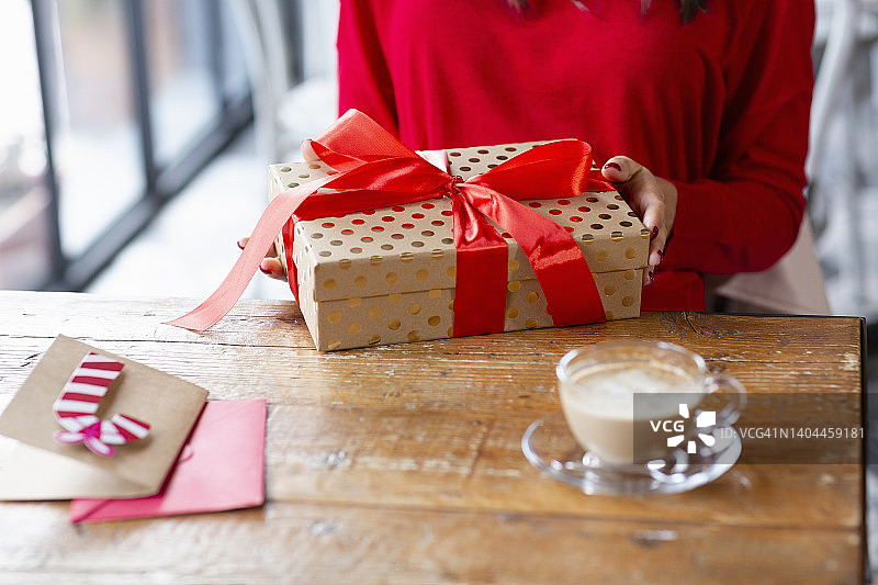 女人带着圣诞礼物和咖啡杯坐在咖啡馆的桌子旁图片素材