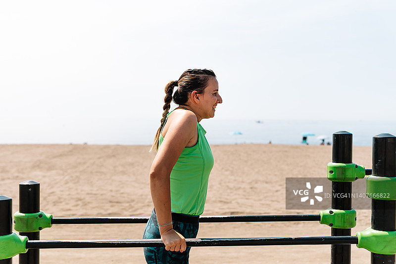 在沙滩上做运动的女人。在一些杠铃上做三头肌训练。图片素材