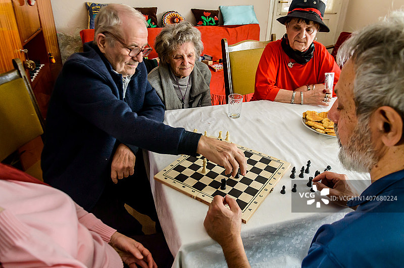 一群老年人在一个社交中心下棋，玩得很开心。图片素材