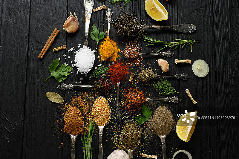 色彩丰富的各种香草和香料烹饪在黑色木制质朴的背景图片素材