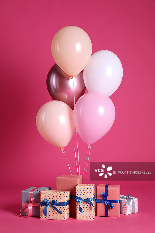 许多礼品盒和气球靠近亮粉色的背景图片素材