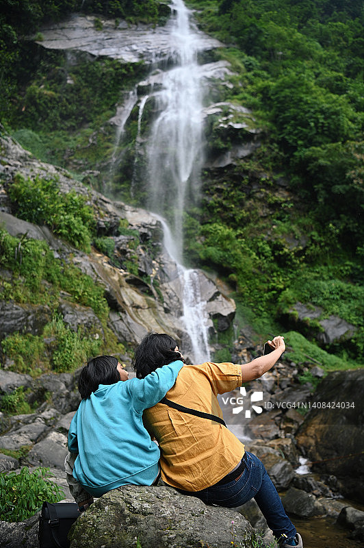 母女俩坐在瀑布旁自拍图片素材