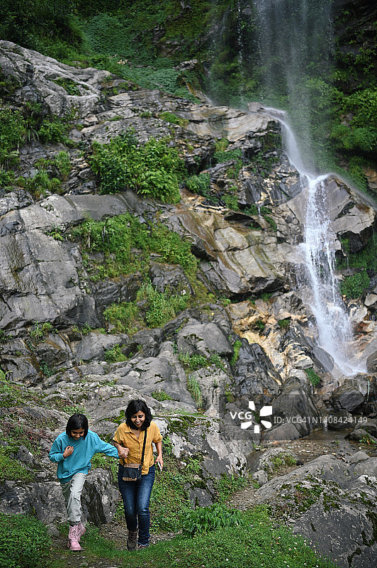 母女俩走在瀑布前图片素材