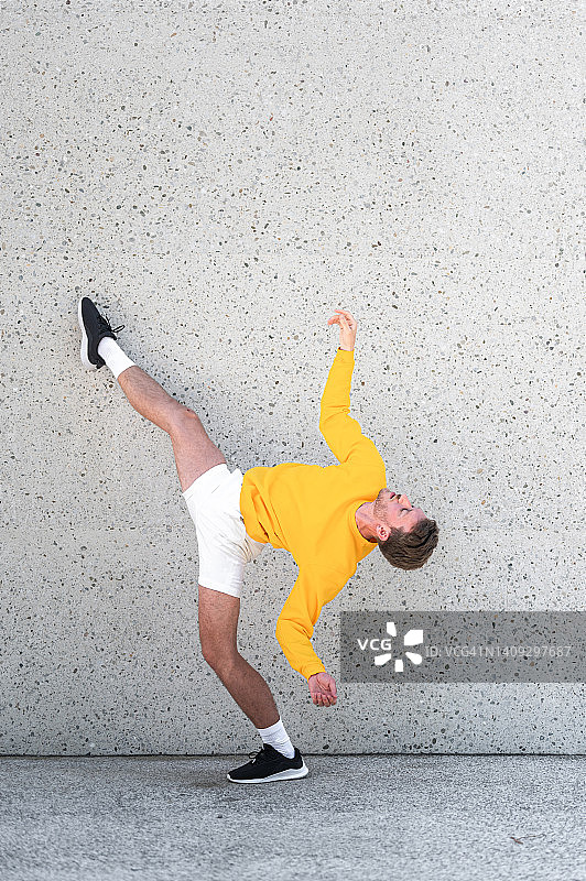 男舞者在水泥墙旁摆姿势图片素材