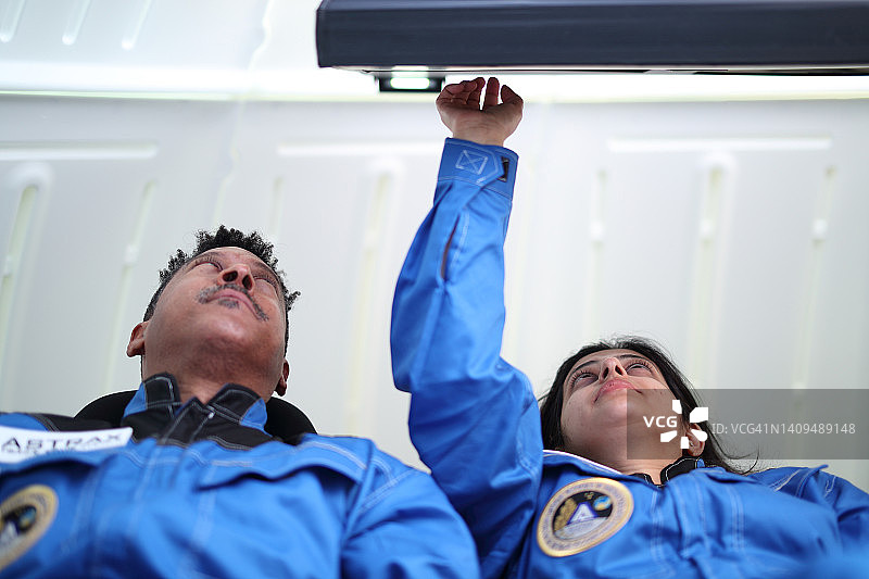 商业太空旅行者躺在座位上，在飞船内。图片素材