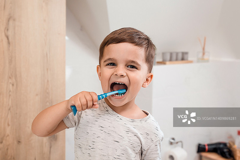 孩子刷牙。孩子们的牙刷和牙膏。阳光明媚的早晨，有趣的小男孩在现代化的浴室里刷牙。儿童牙齿卫生及健康图片素材