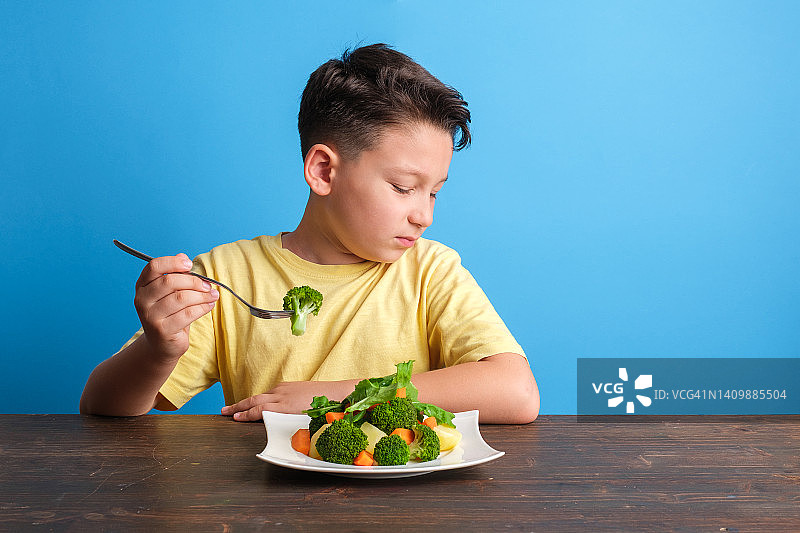 孩子对不得不吃蔬菜很不高兴图片素材