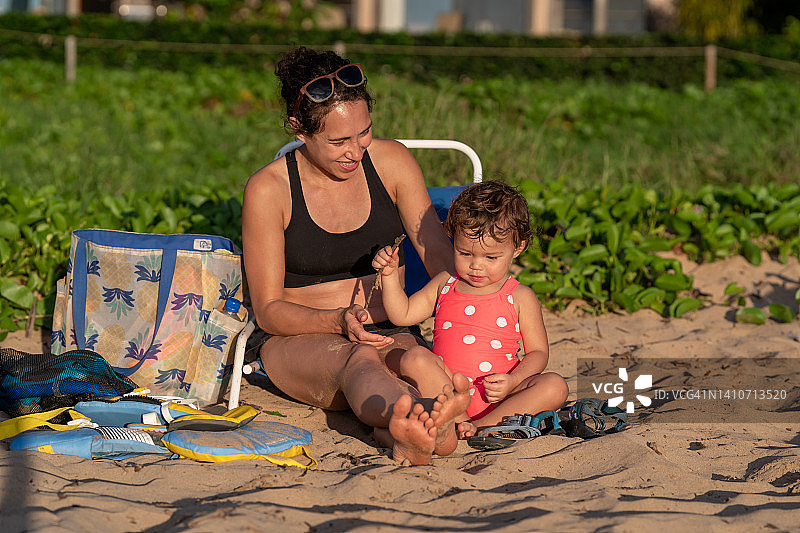 蹒跚学步的小女孩在沙滩上和妈妈玩耍图片素材