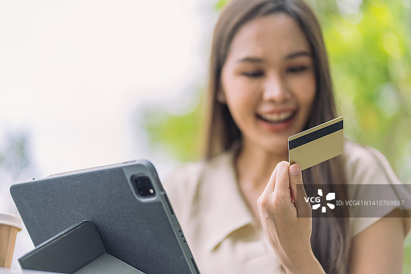 亚洲女性正在网上购物，并用信用卡支付。用智能手机在网上购物，用信用卡进行移动支付图片素材
