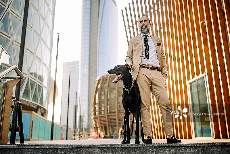 严肃优雅的高级商人和他的狗在城市楼梯上的肖像图片素材