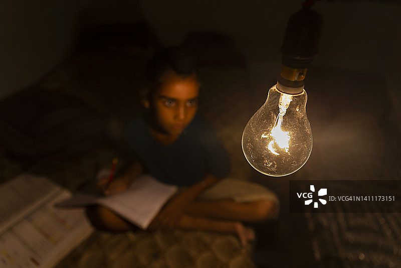 男孩在家学习时看着电灯泡图片素材