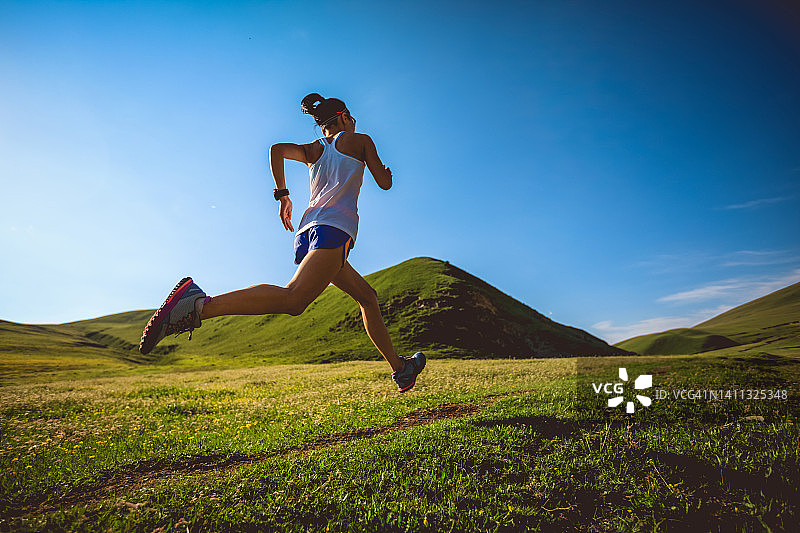 年轻的健身女性在高海拔草原上跑步图片素材