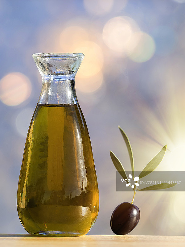 一瓶橄榄油和成熟的橄榄在阳光的照耀下。图片素材