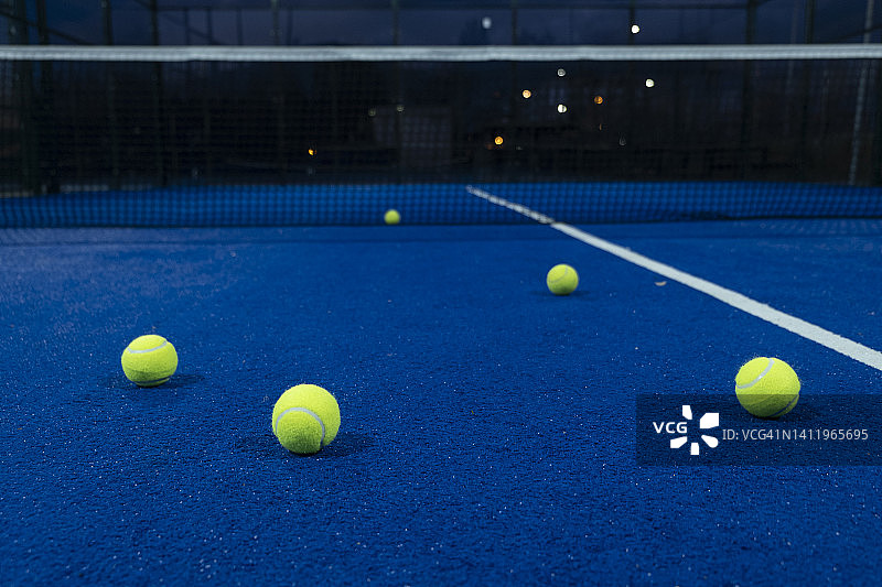 黄昏时蓝色球拍网球场上的五个球，球拍运动概念图片素材