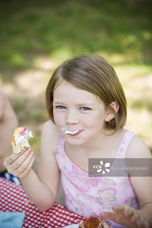 9岁的小女孩在外面野餐时吃了一个纸杯蛋糕图片素材