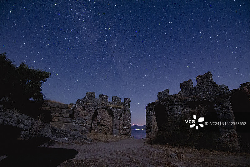 城堡的夜景。在前景中有一座山顶的银河系的星星的视图。夜空自然夏景。英仙座流星雨观测图片素材