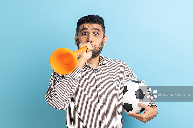 商人拿着扩音器捧着足球，庆祝最喜爱的足球队的胜利。图片素材