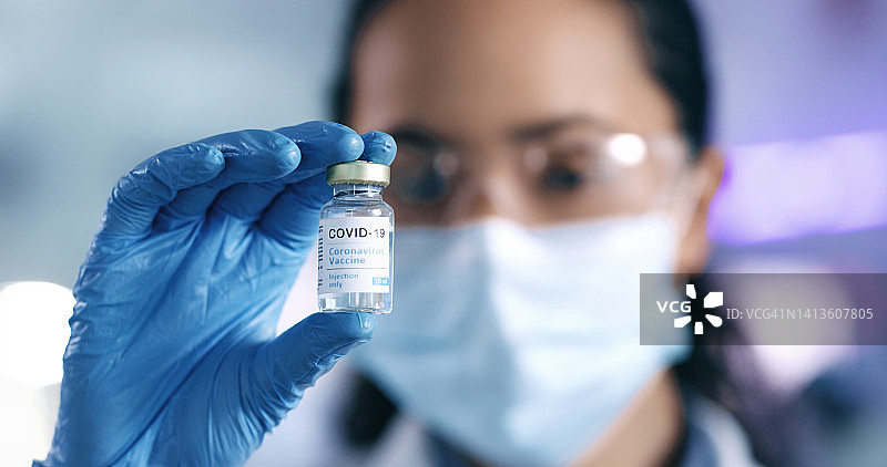 在实验室工作时拿着治疗新冠病毒的疫苗药物。疫苗接种和研究帮助我们保护和治疗疾病。科学家手持药瓶的特写图片素材