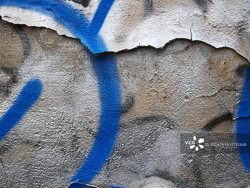 在法国巴黎，蓝色、银色、白色和黑色的油漆喷在开裂的混凝土墙上图片素材