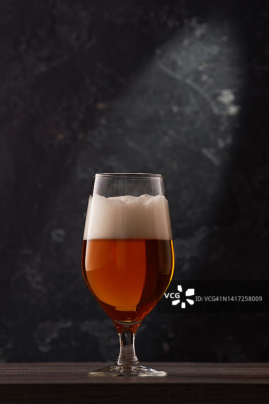 黑色背景上的郁金香杯啤酒。图片素材