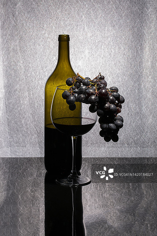 静物与红酒在一个玻璃杯和瓶子和一串成熟的葡萄图片素材