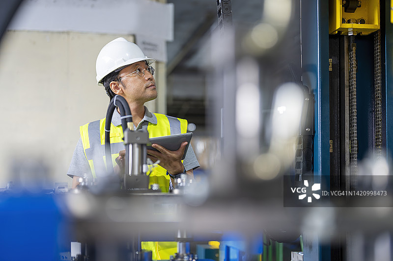 日本工程师在工厂安装过程中检查机器人协同输送系统。图片素材