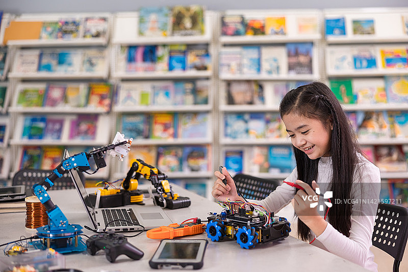 亚洲女孩在教室里工作机器人汽车模型。教育创新理念。图片素材