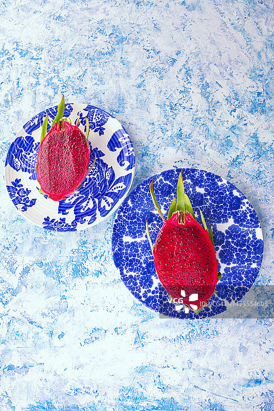 鸟瞰新鲜火龙果，火龙果或火龙果切成一半在蓝色图案盘子上的白色和蓝色背景图片素材