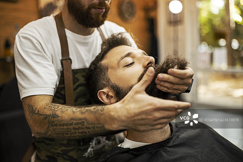 理发师用手给顾客造型胡须图片素材