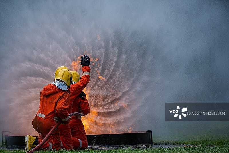 消防队员灭火，消防队员使用灭火器和水管灭火。图片素材