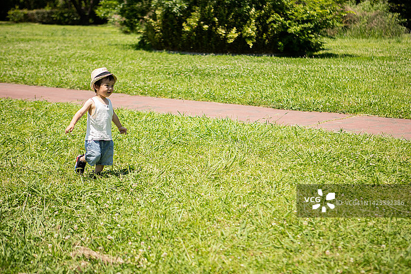 一个一岁的男孩在公园里跑来跑去。图片素材