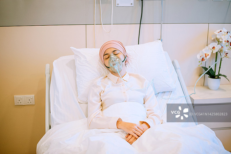 一名亚洲女性癌症病人在医院使用氧气罩图片素材