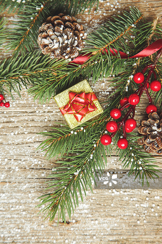 圣诞树的树枝，礼盒，针叶树球果和红色浆果顶视图复制空间在旧的木制背景。圣诞节，寒假，新年的概念。图片素材