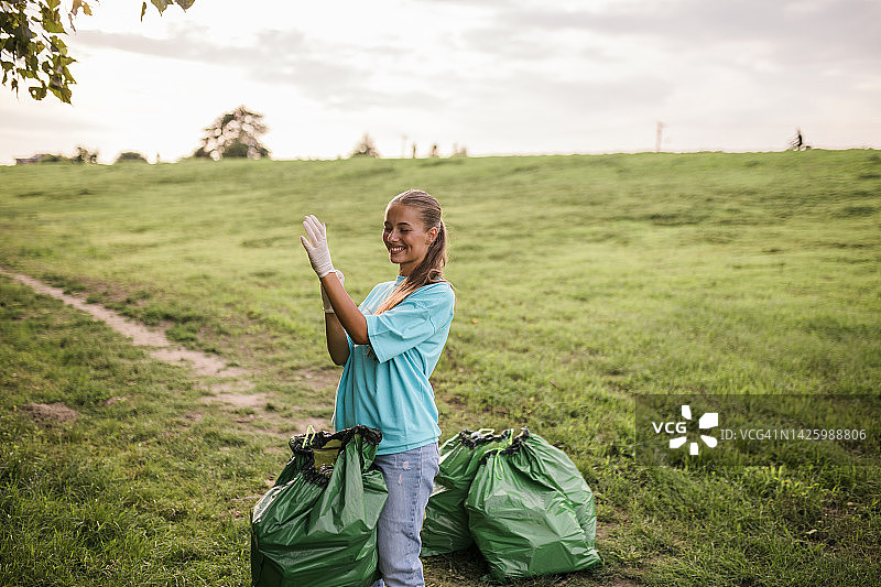 年轻的女志愿者在当地公园清理和收集垃圾。清洁和照顾的概念图片素材