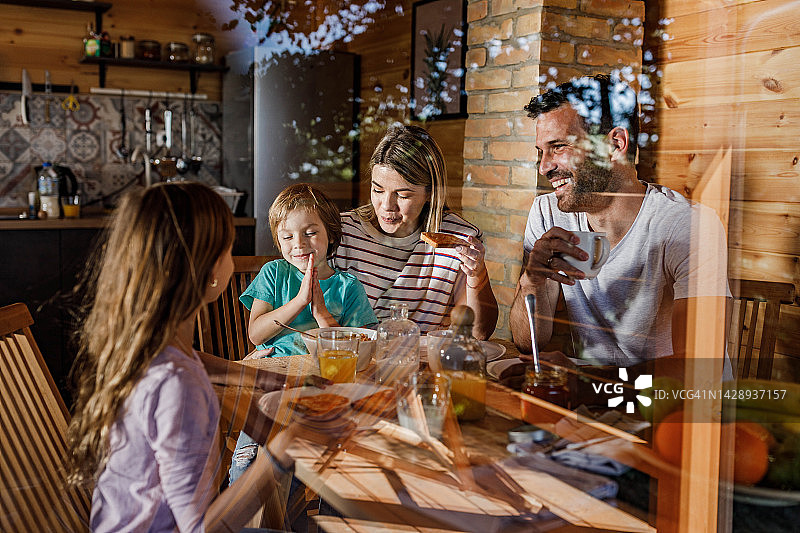 年轻幸福的家庭在餐桌上享受他们的早餐。图片素材