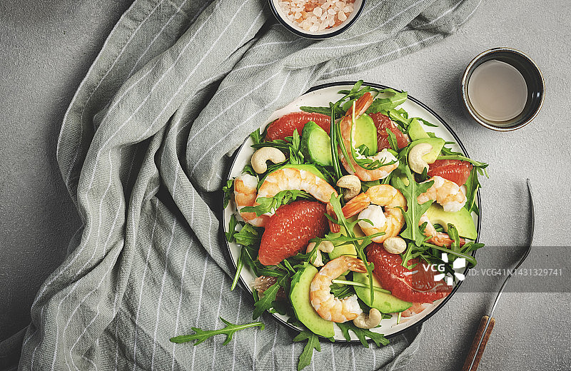 健康新鲜的沙拉配虾，牛油果，柚子，芝麻菜和腰果。灰色石材厨房餐桌背景，俯视图，复制空间图片素材