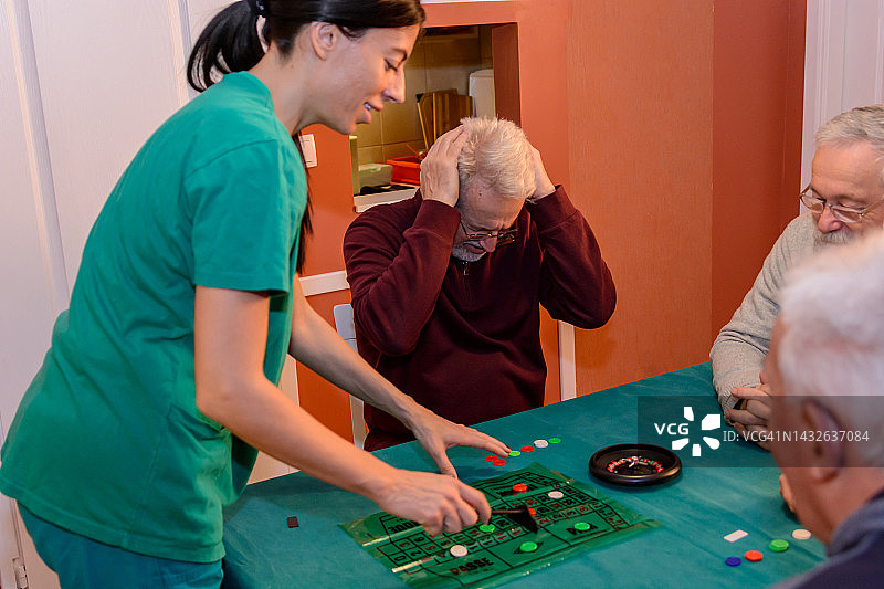在一个社交聚会上，一群老人正在玩轮盘赌游戏，玩得很开心。图片素材