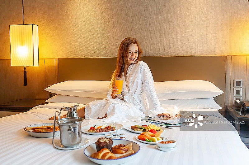 床上的食物供应在豪华酒店，度假的女人享受早餐图片素材