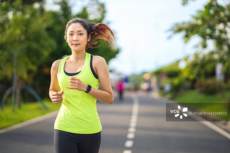 年轻的健身运动妇女在公园跑步。健康的健身妇女在户外慢跑。体育与健康概念图片素材