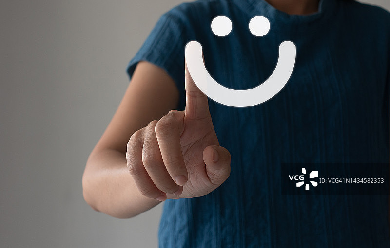 客户的手显示反馈与一个笑脸标志的背景。客户服务，服务评级，反馈，评审，满意概念。图片素材