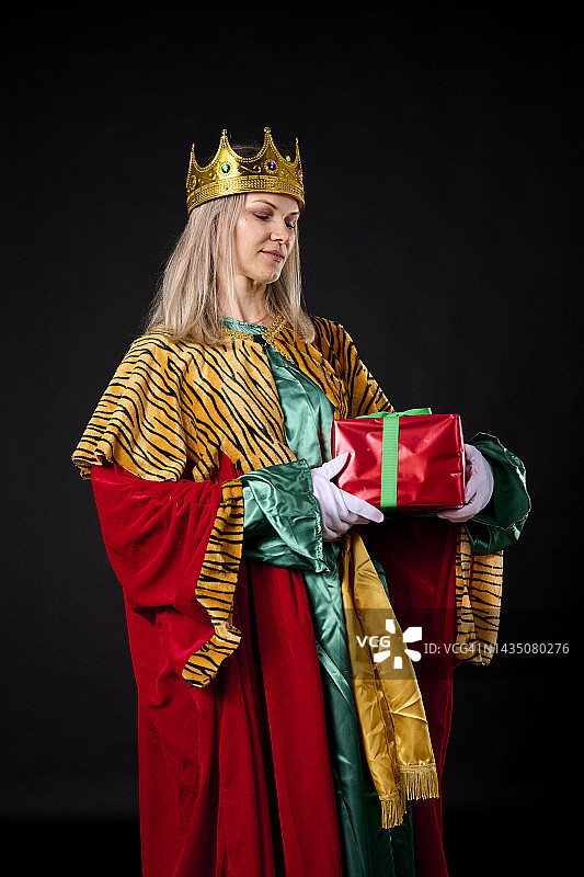 年轻的金发女郎，戴着皇冠，穿着红裙子，带着圣诞礼物图片素材