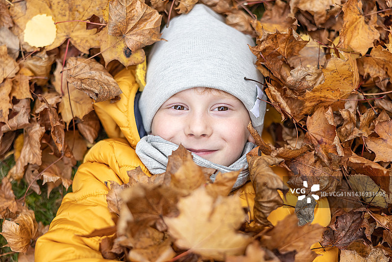 俯视图，可爱的小男孩躺在秋天的树叶。图片素材