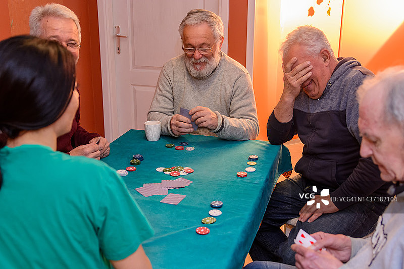 一小群老年人在家里打牌，玩得很开心。图片素材