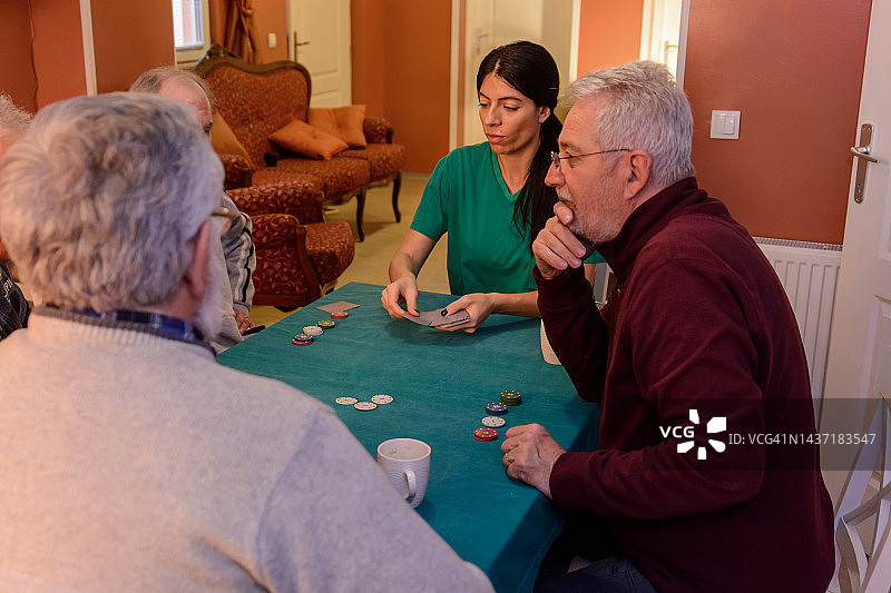 老人们在社交会上打牌，玩得很开心。图片素材