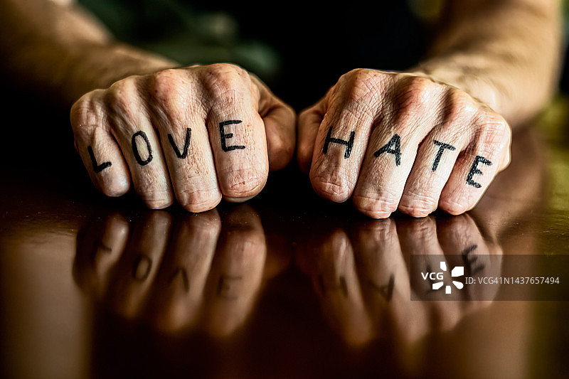 一个男人的拳头特写，他的手指上写着爱和恨。图片素材