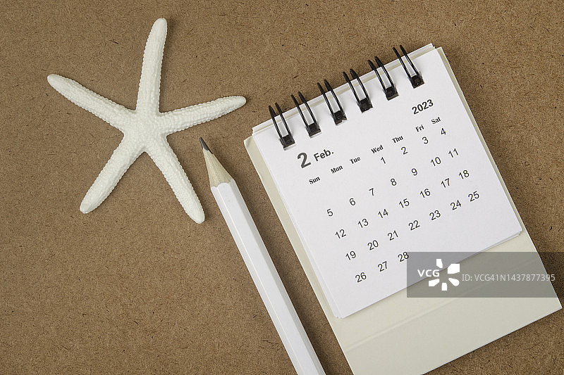 2023日历桌:二月是组织者用海星和棕色纸背景的白铅笔做计划和截止日期的月份。图片素材