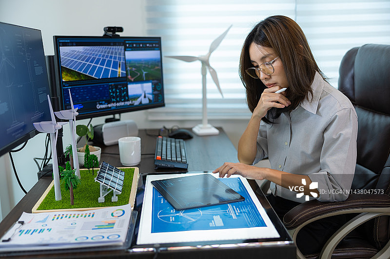 亚洲女工程师肖像与计算机，风力涡轮机太阳能电池板模型发展可持续能源项目。图片素材