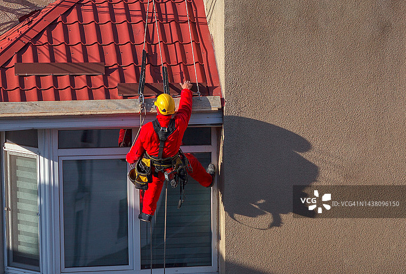 工人吊在绳索上修补屋顶图片素材