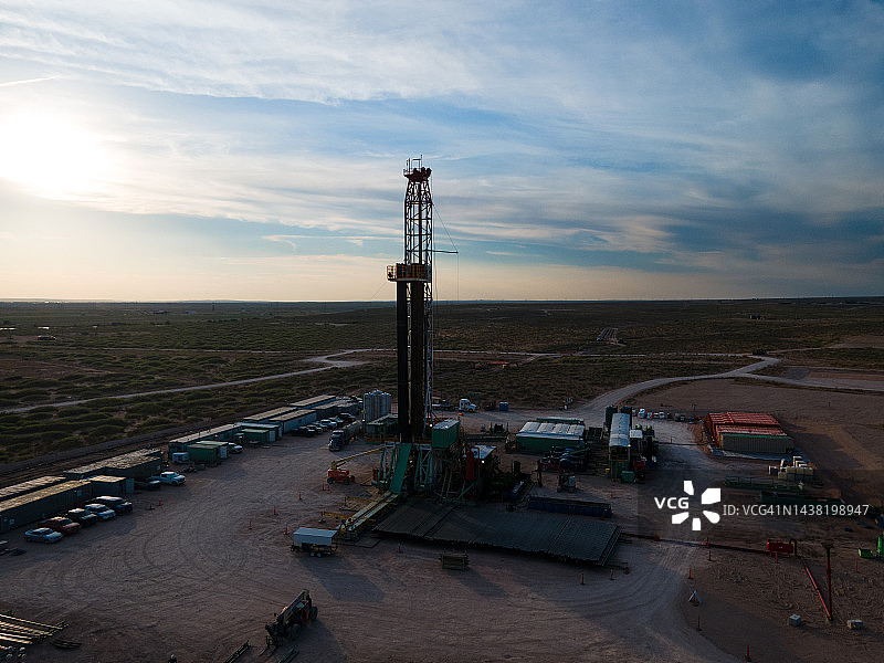 在西德克萨斯州或新墨西哥州的二叠纪盆地的日落天空下，一个石油压裂钻井平台的黄昏镜头图片素材